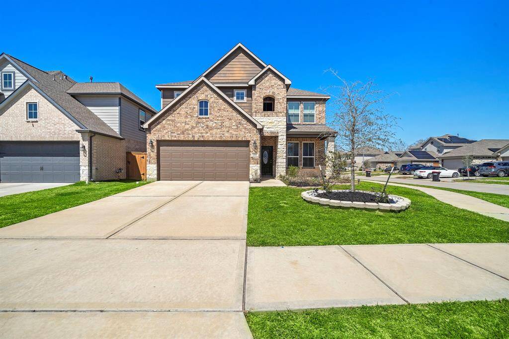 This is a modern two-story brick home with a spacious driveway and attached garage. It features a well-maintained front lawn with a small landscaped area. The neighborhood appears to be well-kept and residential.