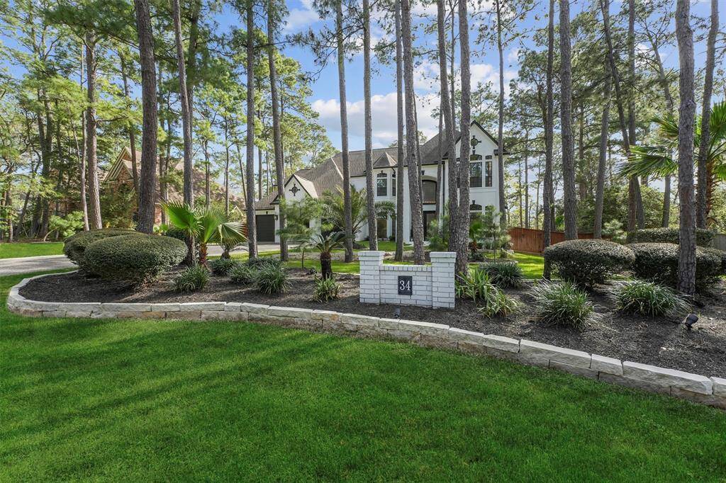This photo shows a spacious, elegant two-story home surrounded by tall trees and manicured landscaping. The property features a lush green lawn, a curved driveway, and a welcoming entrance. Ideal for buyers seeking a serene, natural setting.