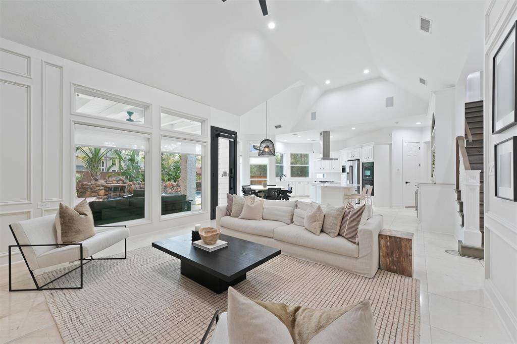 This spacious living area features a bright, open layout with high ceilings and modern finishes. Large windows offer ample natural light and views of the outdoor space. The room connects seamlessly to a sleek, contemporary kitchen, perfect for entertaining and family living.