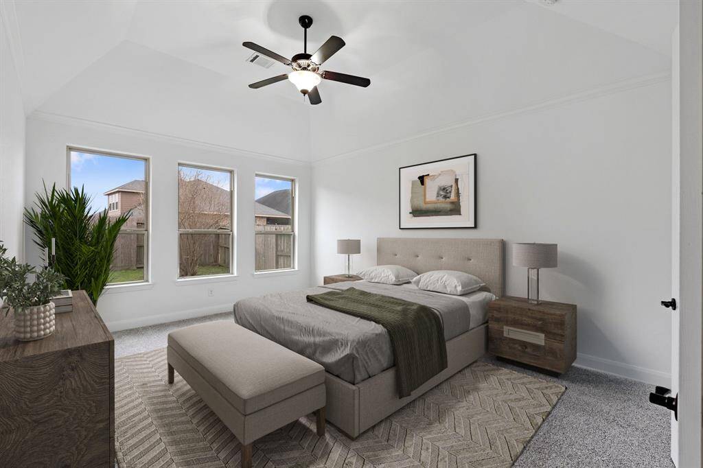This inviting primary bedroom, conveniently located on the first floor, features soft carpet, an abundance of natural light from multiple windows, and a striking high sloped ceiling that adds elegance and character to the space. *Virtually Staged*