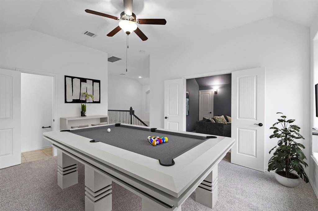 The spacious game room features cozy carpet, ample natural light from the windows, and a charming sloped ceiling, creating a perfect space for entertainment and relaxation. *Virtually Staged*