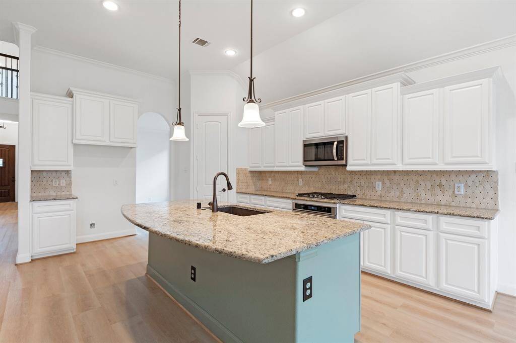This stunning kitchen features elegant white cabinets, sleek granite countertops, and a spacious kitchen island with a built-in sink, combining style and functionality effortlessly.