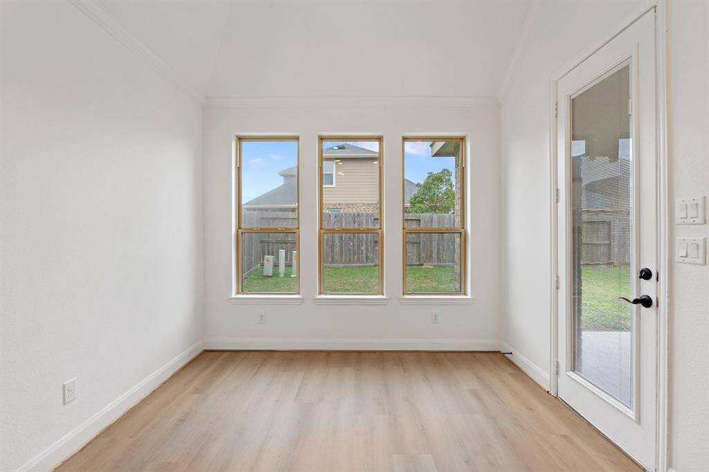 The breakfast area is filled with natural light from multiple windows, features durable vinyl flooring, and offers easy access to the backyard for seamless indoor-outdoor living.