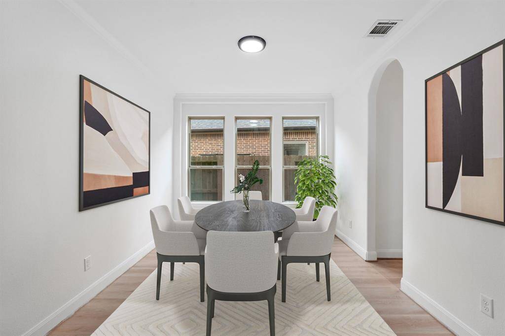 The elegant formal dining room, located next to the kitchen, features expansive windows that fill the space with natural light, stunning vinyl flooring, and the perfect ambiance for hosting unforgettable gatherings. *Virtually Staged*