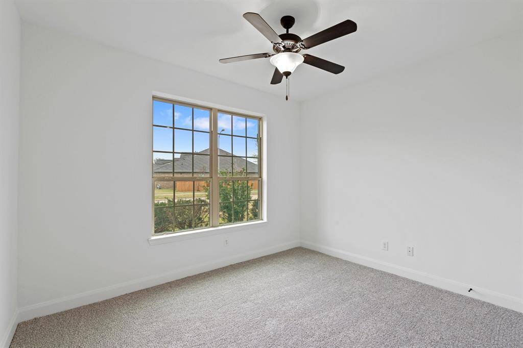 This spacious first-floor bedroom offers plush carpeting, a large window for natural light, and a sleek ceiling fan, creating a comfortable and inviting retreat!