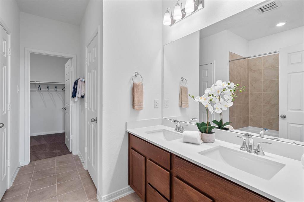This primary bathroom is definitely move-in ready! Featuring an oversized tub/shower combo with tile surround, stained cabinets with light countertops, large walk-in closet, high ceilings, neutral paint, sleek and modern finishes.