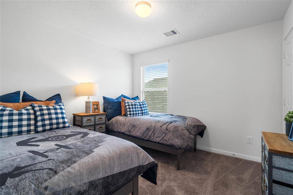 Secondary bedroom features plush carpet, neutral paint, lighting, large windows with privacy blinds and ample sized closet space.
