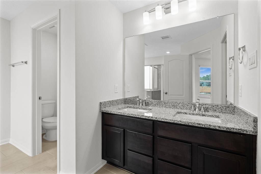 This large primary bath is spacious enough to share! With separate vanities, plentiful cabinet and counter space, you are sure to have private area while sharing this bathroom!