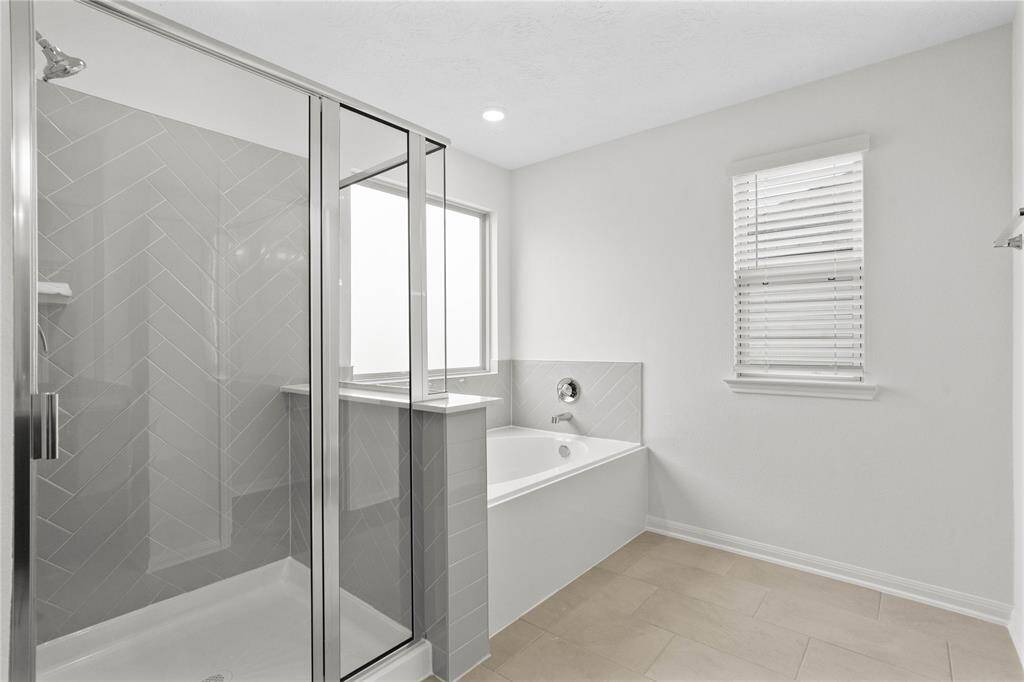 This primary bathroom is definitely move-in ready! Featuring a walk-in shower with tile surround, separate garden tub for soaking after a long day with custom tile detailing, custom paint, sleek and large windows to bring in the natural light.