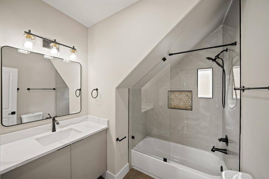 This secondary bathroom is complete with quartz countertops and backsplash, and a shower/tub combo.