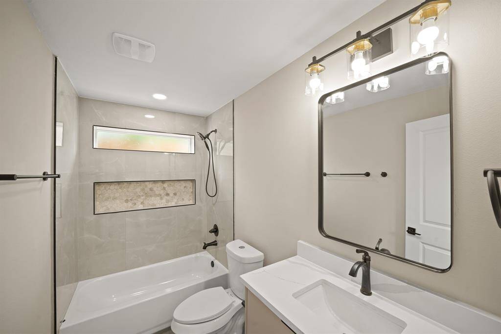 This secondary bathroom is complete with quartz countertops and backsplash, and a shower/tub combo.