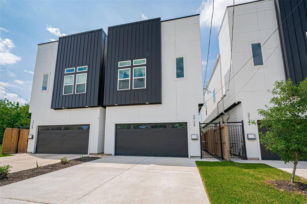Contemporary façade with striking black-and-white contrast, featuring large windows and a 2-car garage.