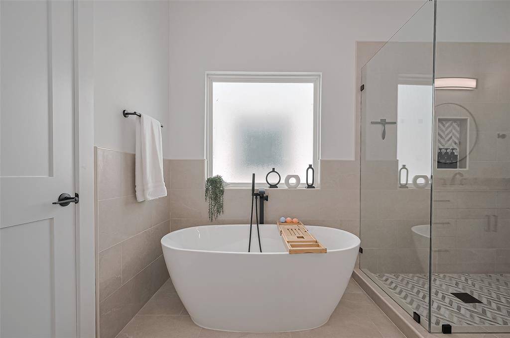 Soak in luxury with a freestanding tub, matte black fixtures, and a sleek frameless glass shower for a spa-like experience.
