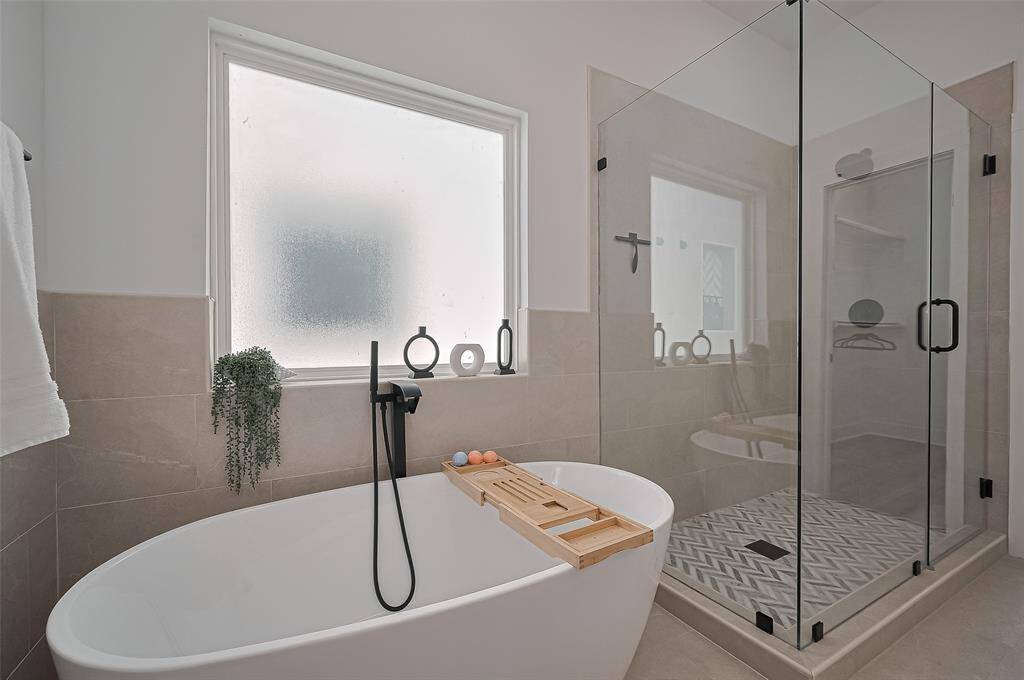 Soak in luxury with a freestanding tub, matte black fixtures, and a sleek frameless glass shower for a spa-like experience.