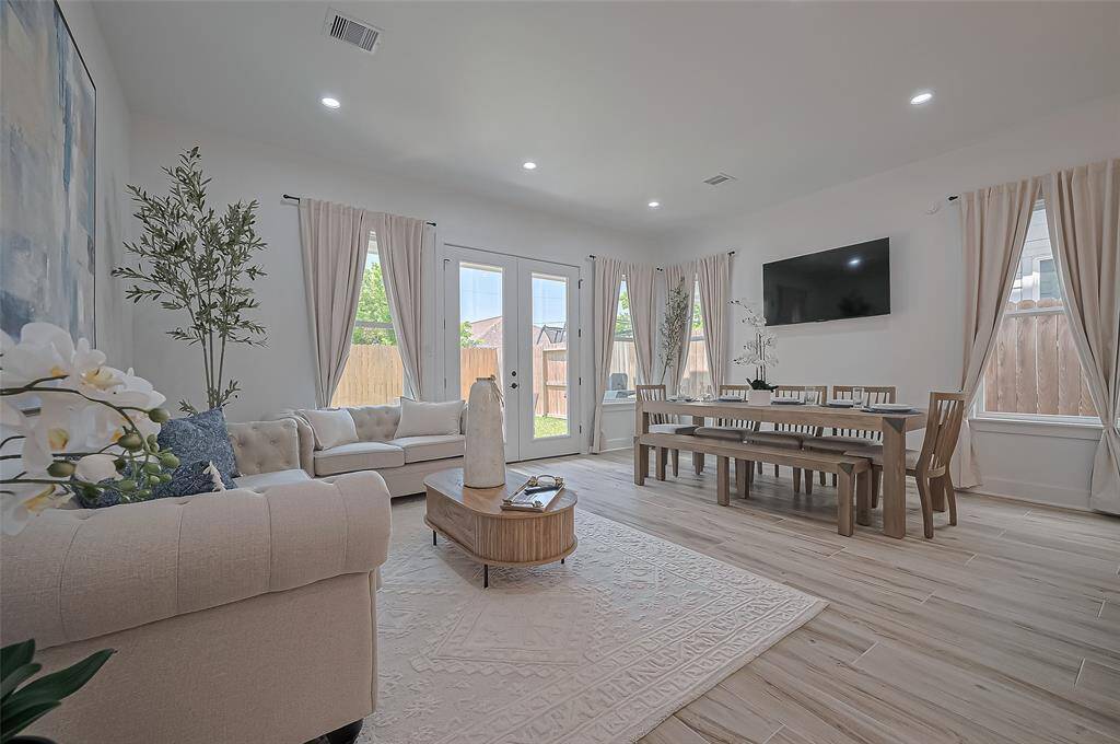 Open-concept living and dining space featuring abundant natural light, soft neutral tones, and seamless access to the backyard through French doors.