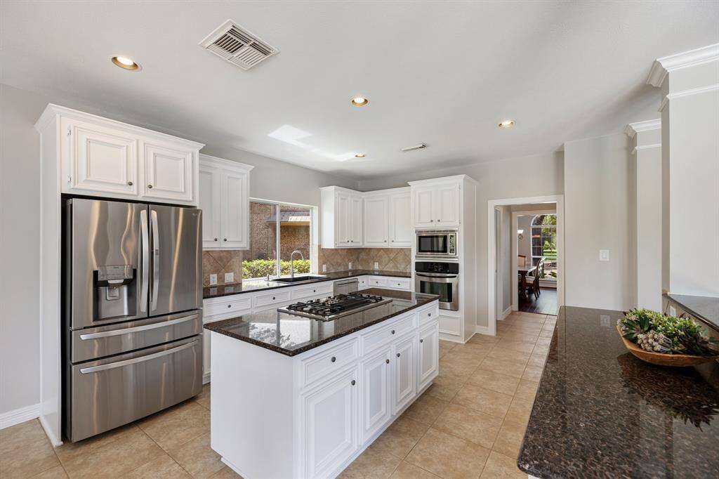 Ample white cabinetry and gleaming granite countertops complement one another in texture and color, while the stainless-steel appliances add balance and sheen.