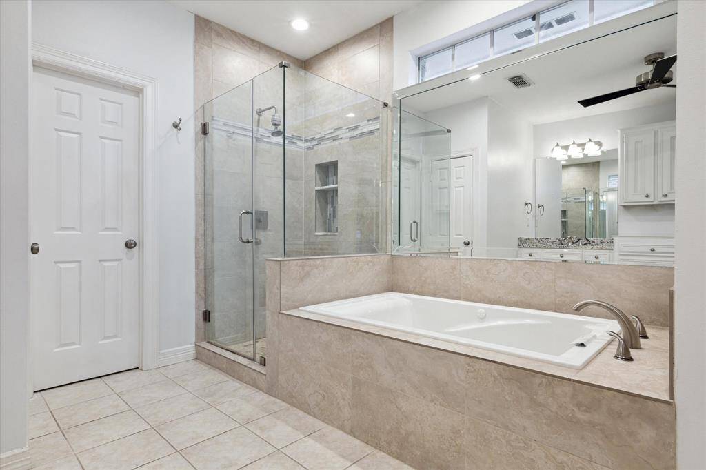 Large primary bedroom featuring an oversized soaking tub and separate standing shower for a spa-like experience.