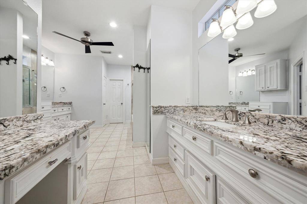 Primary bathroom with separate sinks and an additional vanity, offering convenience and style.