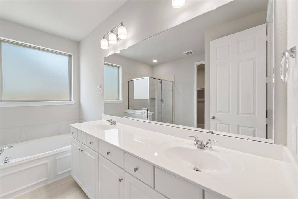 The en-suite bathroom offers a spa-like atmosphere with its elegant design, high end finishes, and tasteful lighting, creating a retreat within your own home.