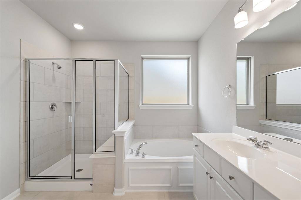 This additional view of your primary bathroom features tile flooring, fresh paint, walk-in shower, a separate garden tub, and a large walk-in closet.