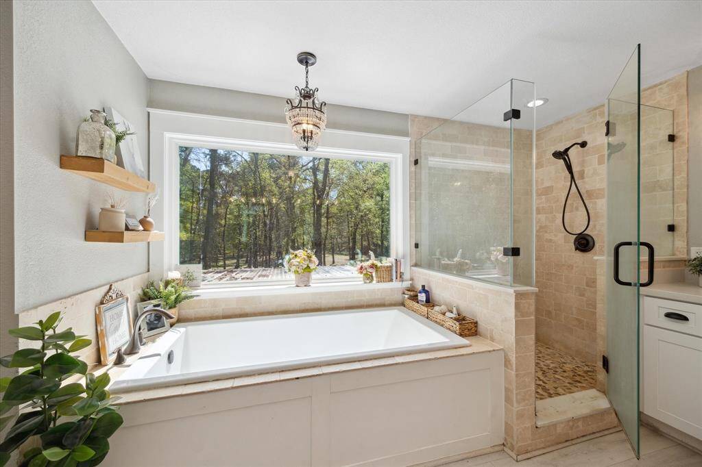 A tranquil primary bathroom awaits you with forest views of your land.