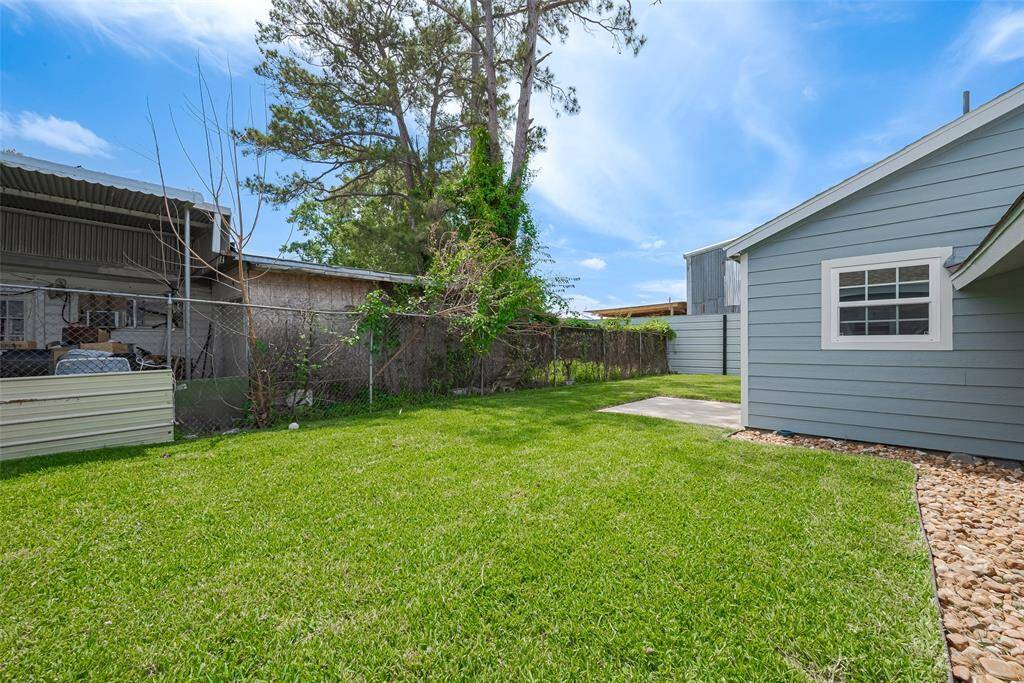 A well-maintained backyard with a grassy lawn, a small concrete patio, and siding on the house. It's bordered by a wooden and metal fence, offering a private outdoor space.