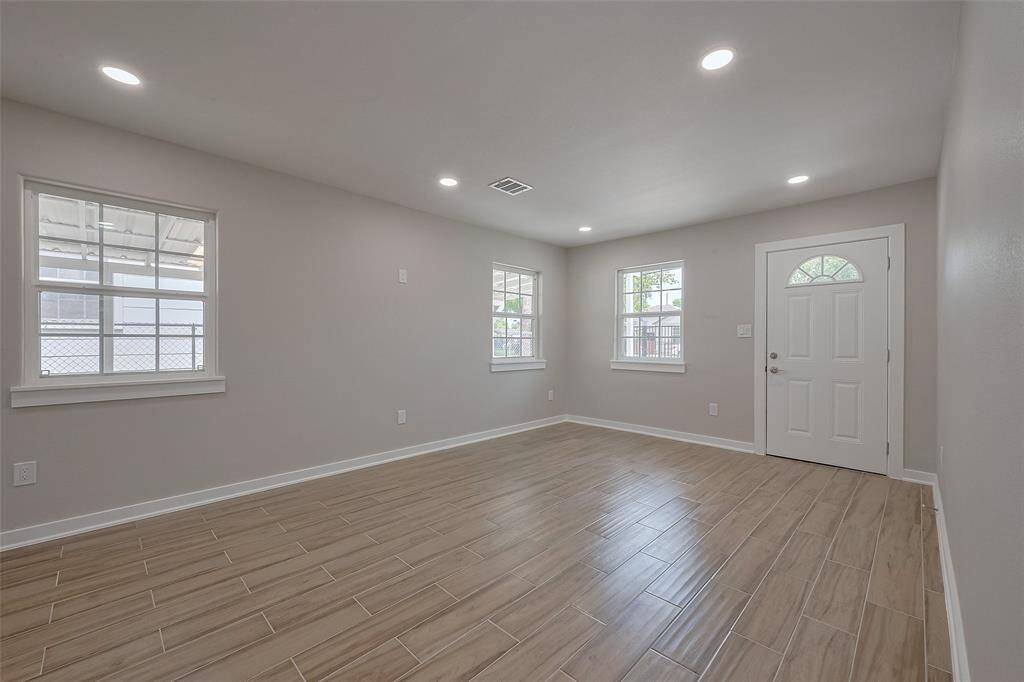 Bright and spacious living area with recessed lighting, tile flooring, and large windows. Perfect for a cozy setup.