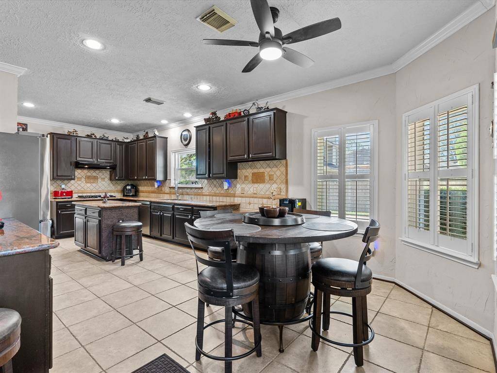 At the far end of the kitchen features a built-in desk station. And windows offering natural light brightening the kitchen from all corners, plantation shutters adding a touch of elegance, and views of the pool