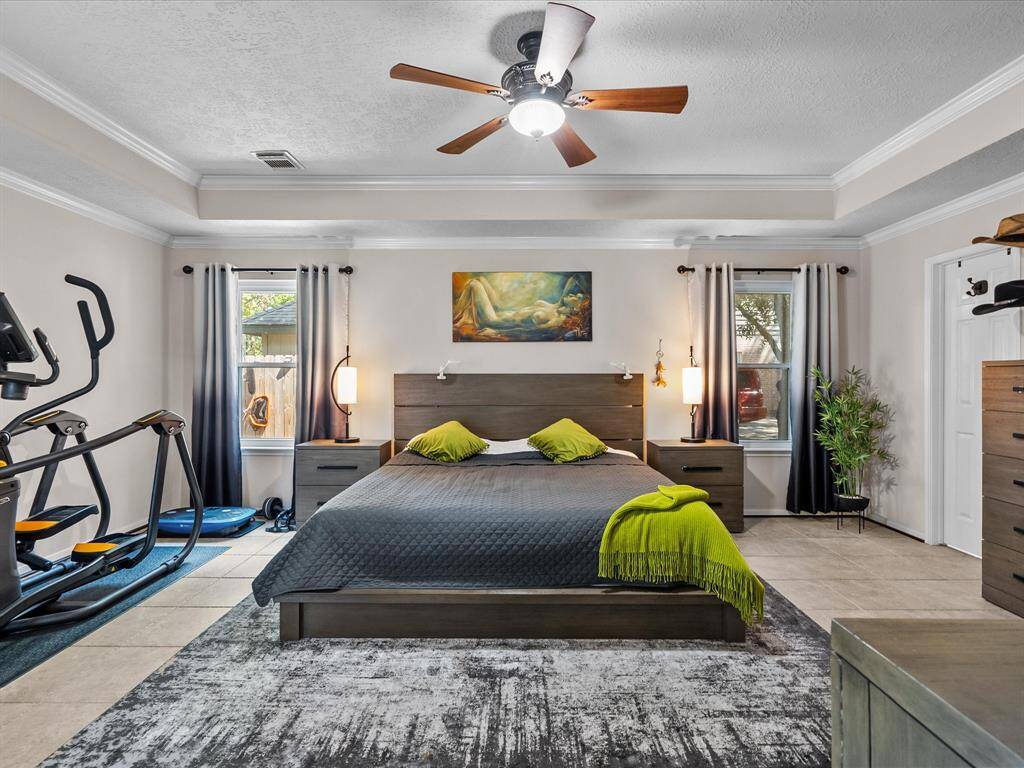 The spacious downstairs primary retreat features crown molding, and tile floors, and a large closet
