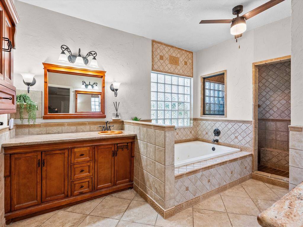 The primary bathroom with his and hers granite vanities, copper inspires sinks, jetted tub and a large walk-in shower with a built-in bench seat.