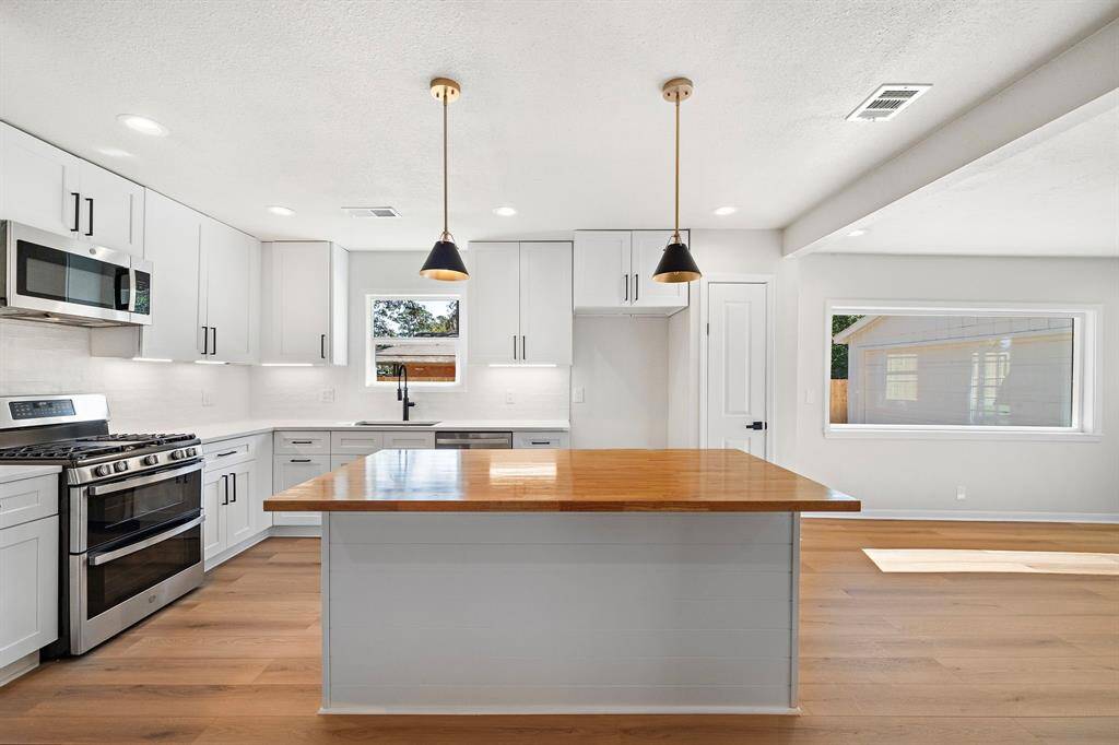 Kitchen with new cabinets and designer selected finishes and fixtures, including the butcher block island, flows directly into the window filled formal dining room