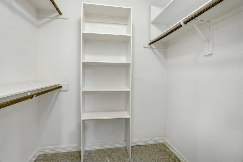 The primary closet offers two sides of hanging space with built-in storage between.