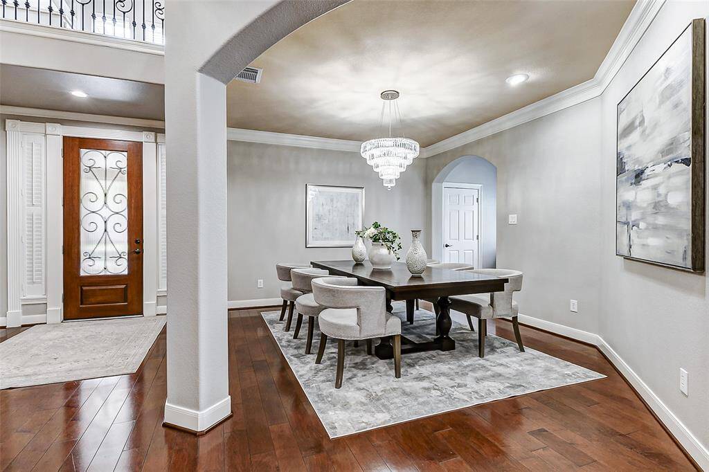 This sophisticated dining space is framed by graceful archways and features gleaming wood floors and a stunning chandelier centerpiece. Positioned just off the entry, it offers a grand yet intimate setting for gatherings.