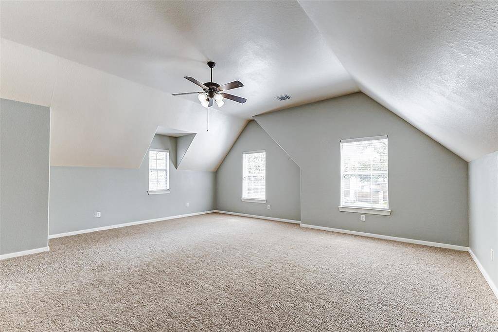 This generously sized room with cozy sloped ceilings and multiple windows offers plenty of natural light and flexibility — perfect as a game room, media space, or creative studio.