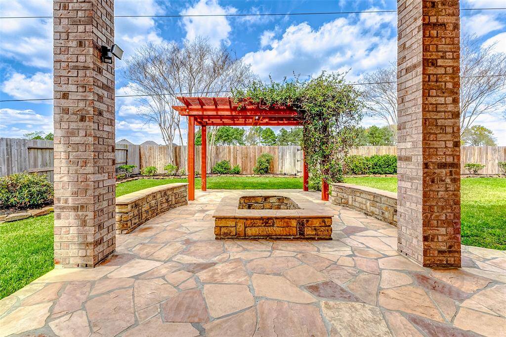 Step into your private outdoor escape: a spacious covered patio with built-in seating and a pergola, perfect for relaxing or entertaining. It overlooks a lush lawn with ample room to play, garden, or unwind in the open air.