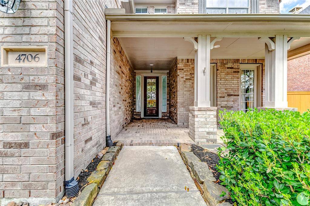 A covered porch framed by stately columns leads to the recessed front entrance, offering both architectural depth and shelter. The elegant entryway sets the tone for the refined interiors beyond.