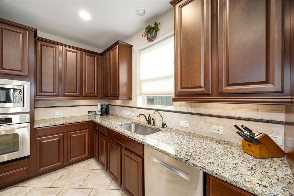 This kitchen is by far any chef’s dream! This spacious kitchen features large windows, high ceilings, dark stained wood cabinets, granite countertops, SS appliances, modern tile backsplash, recessed lighting with additional custom pendant lighting, extended counter space, granite kitchen island with double sink and space for breakfast bar and a walk-in pantry all overlooking your huge family room.