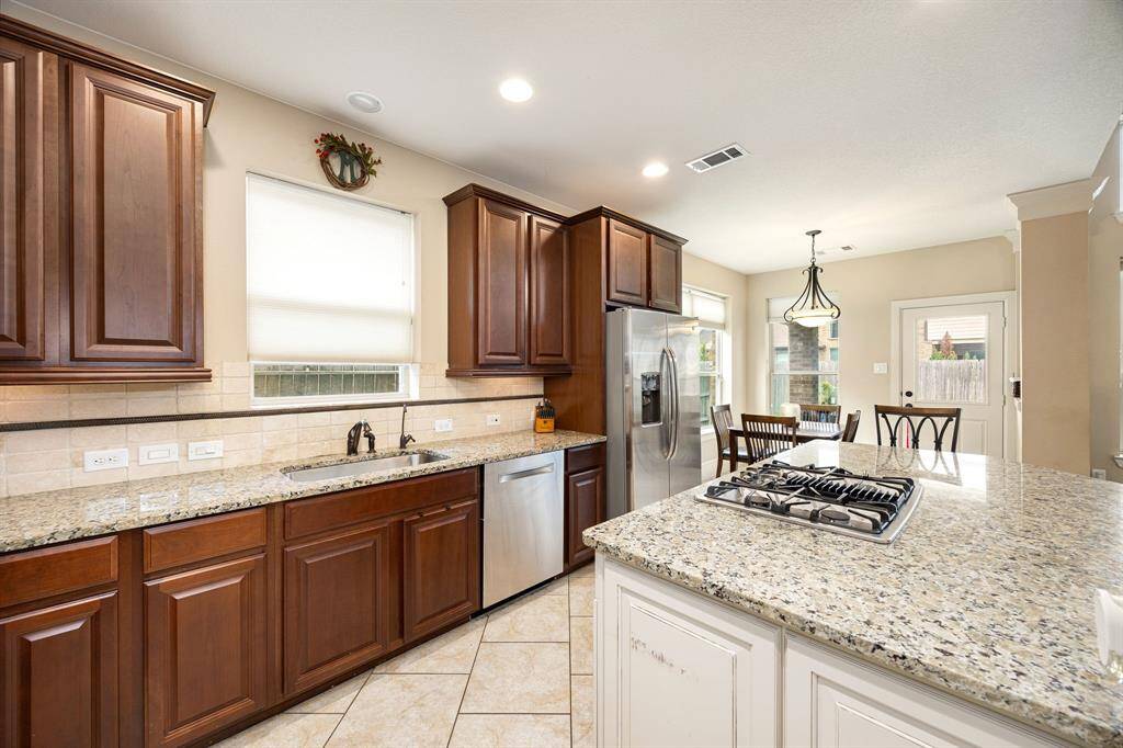 This stunning kitchen displays such a beautiful contrast with the dark stained cabinets, custom neutral paint, granite countertops, light modern backsplash, and SS appliances, oversized kitchen island with extra storage, breakfast bar, recessed lighting, high ceilings and walk in pantry.