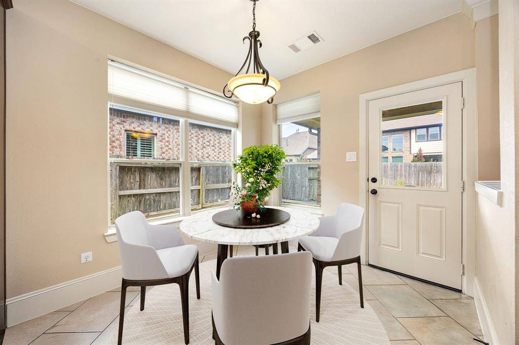 This lovely breakfast area is perfect for starting the day out on the right foot.  This space showcases custom paint, high ceilings, hanging pendant light, recessed lighting, large window adding to the ample natural light in the kitchen, beautiful chair rail and molding and tile flooring. *Virtually Staged