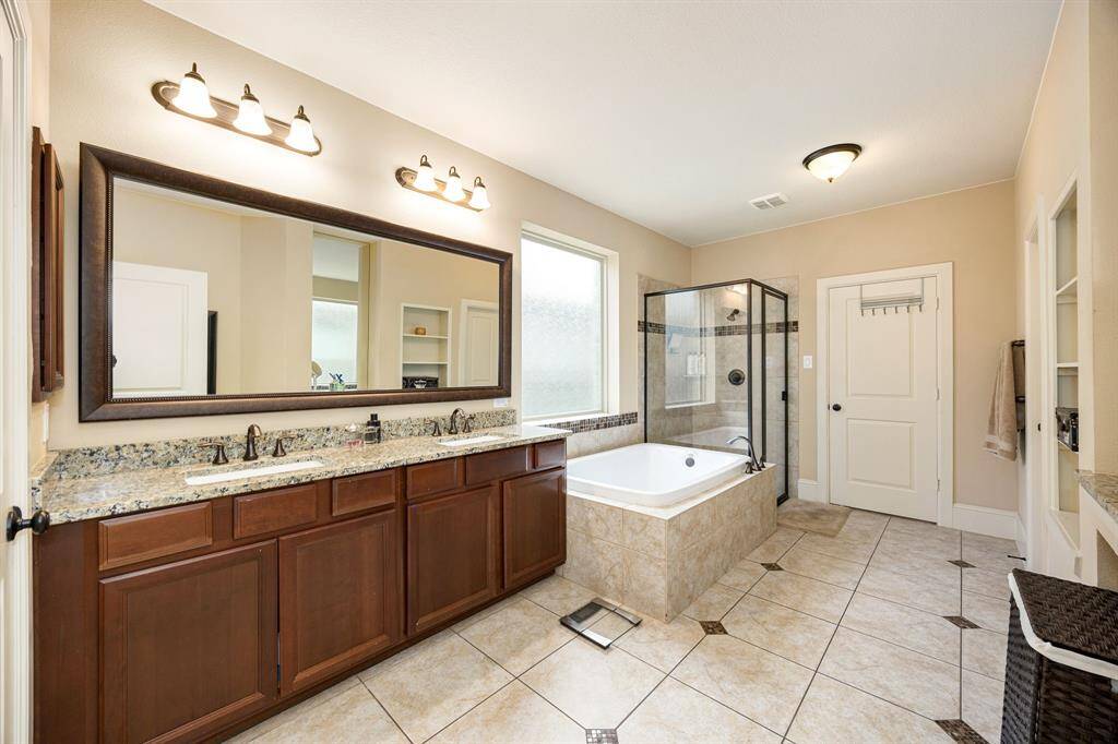 This primary bathroom is definitely move-in ready! Featuring a dark framed walk-in shower with tile surround, separate garden tub for soaking after a long day with custom tile detailing, dark stained cabinets with light countertops, spacious walk-in closet with shelving, high ceilings, custom paint, sleek and dark modern finishes.