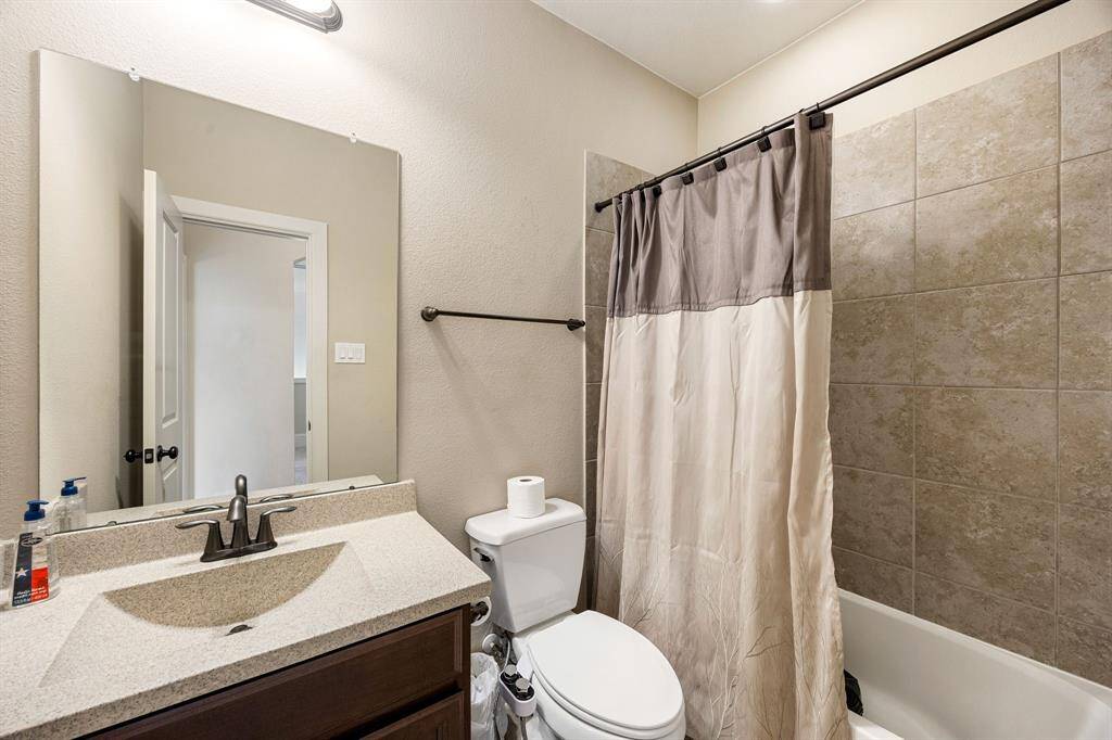 Secondary bathroom features light countertops and cabinets, custom paint, shower/tub combo with tile surround, large mirror, tile floors, sleek fixtures and modern finishes, plenty of space to accommodate any visiting family or guests.