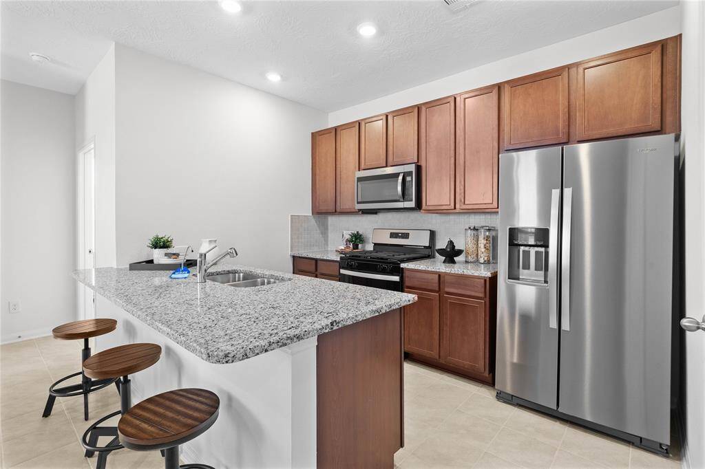 Additional view of this stunning kitchen! Featuring stained cabinets, granite countertops, modern backsplash, stainless steel appliances, recessed lighting, and custom paint.