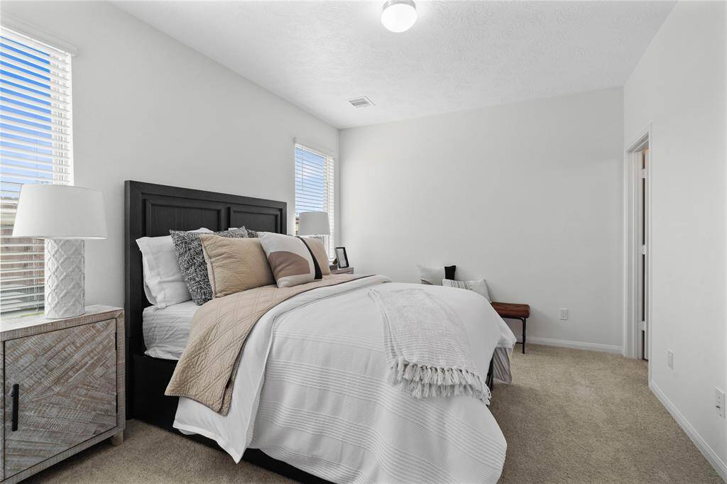 Come and unwind after a long day in this magnificent primary suite! This spacious room features plush carpet, warm paint, high ceilings, and large windows with privacy blinds.