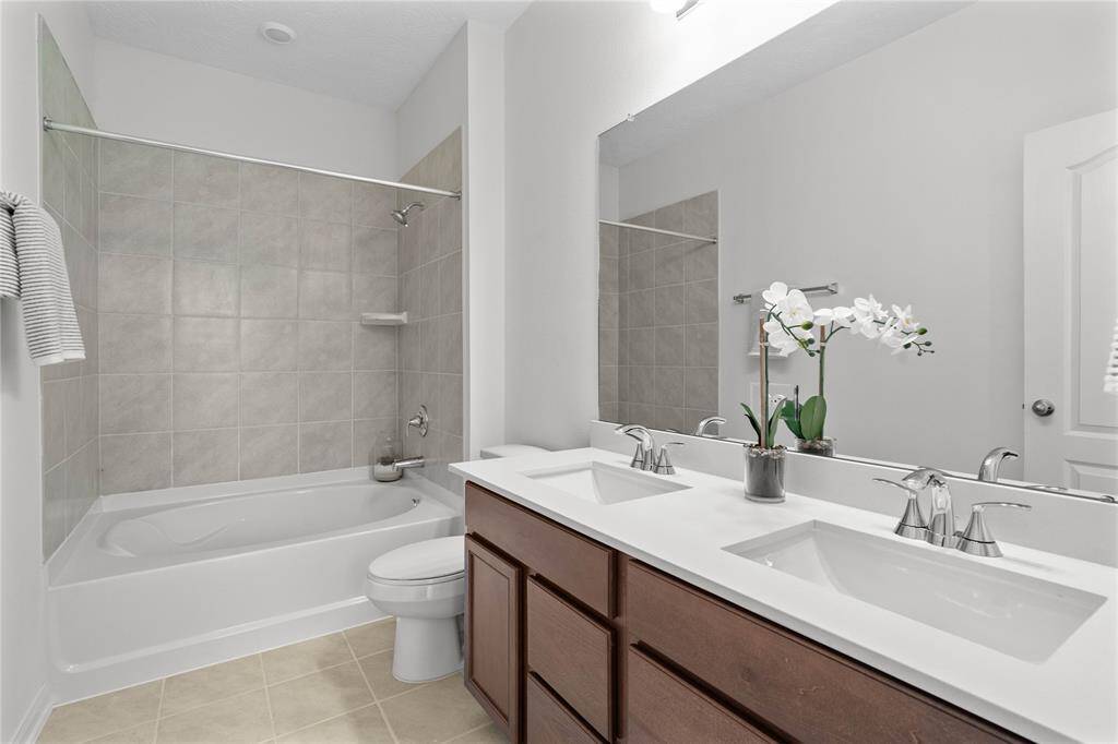 This primary bathroom is definitely move-in ready! Featuring an oversized tub/shower combo with tile surround, stained cabinets with light countertops and dual vanities, high ceilings, custom paint, sleek and modern finishes.