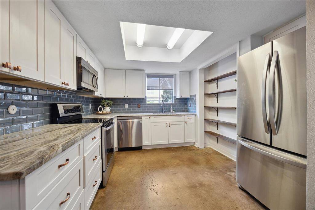 Bright and open kitchen with updated counters, backsplash and modern open shelving for ample storage.