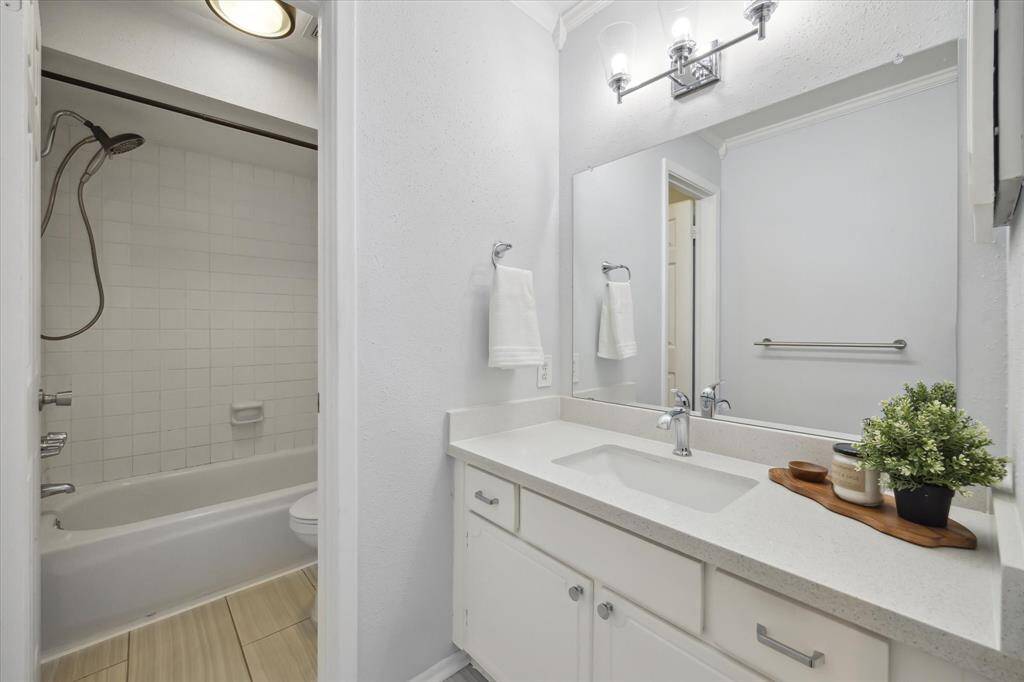 This bathroom features a clean, modern design with updated Silestone countertops and new lighting fixtures.