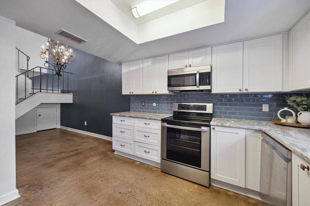 The beautiful modern kitchen with sleek stainless steel appliances, white cabinetry, and a stylish blue tile backsplash.
