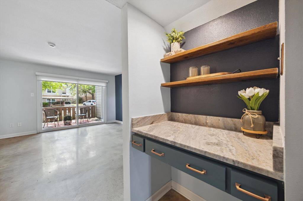 A stylish nook with open wooden shelves and a granite countertop, ideal for storage or display.