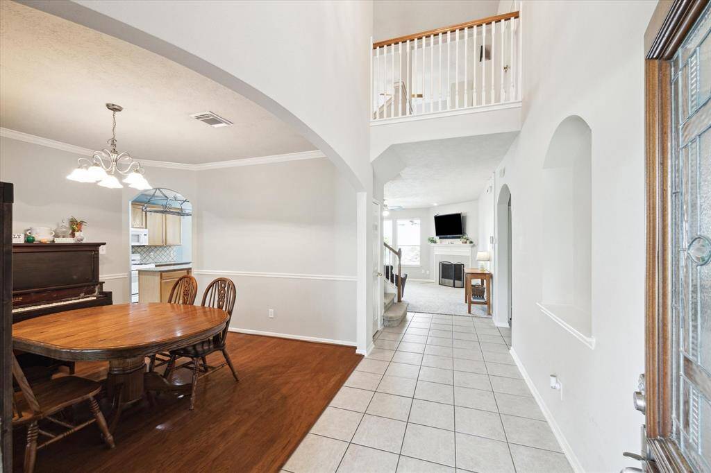 This inviting home features a bright dining area with wooden flooring Entry with tiled flooring. The open layout includes a high ceiling, an overlooking balcony, and a fireplace, providing a warm and spacious atmosphere.