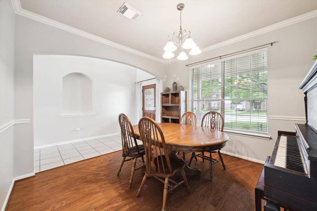 This photo showcases a bright dining room with wood flooring, a large window.